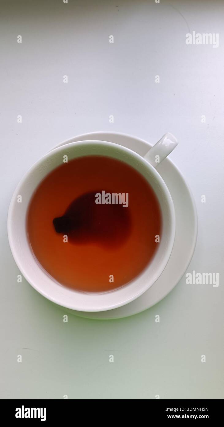 Nahaufnahme einer Tasse mit traditionellem fermentiertem Pu-erh-Tee. Ein sauberer weißer Hintergrund unterstreicht die satte Farbe und Einfachheit. Ideal für Themen wie Hea Stockfoto