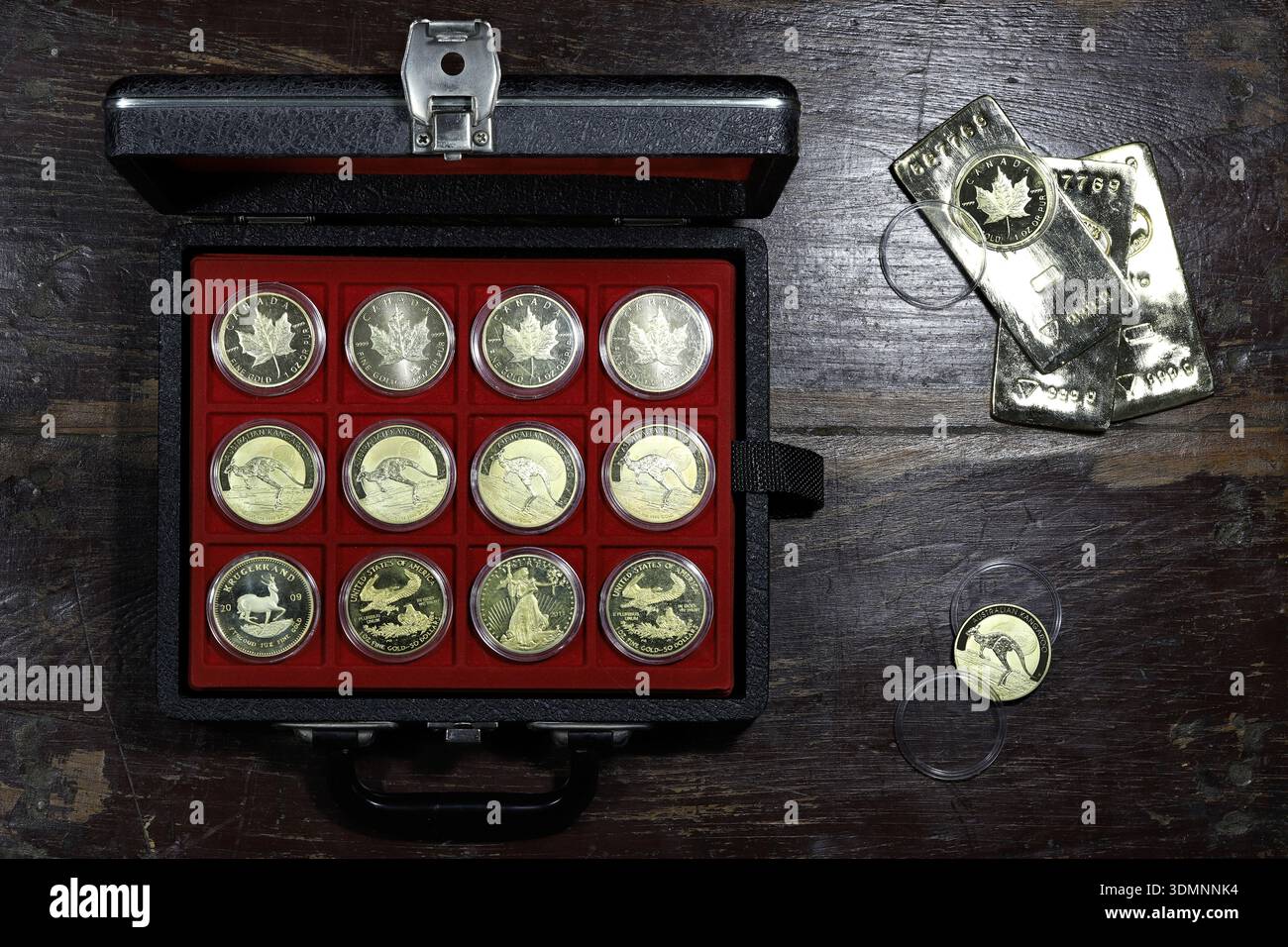 Verschiedene gekapselte 1 Unze Goldbarren in einem Münzkasten auf rustikalem hölzernem Hintergrund Stockfoto