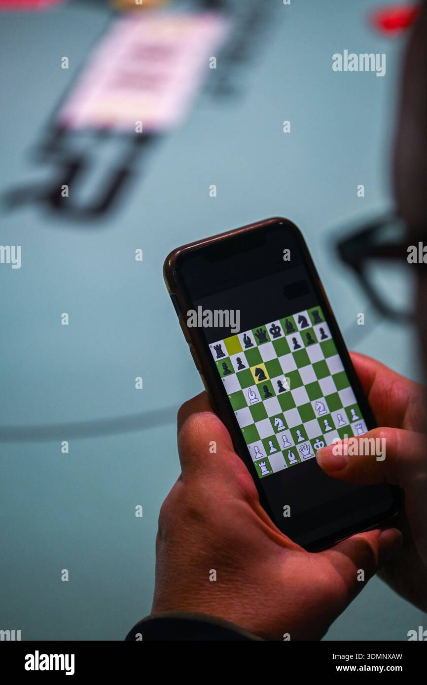 Ansicht einer nicht identifizierbaren Person, die Schach spielt, während ein Pokertisch im Hintergrund stattfindet Stockfoto