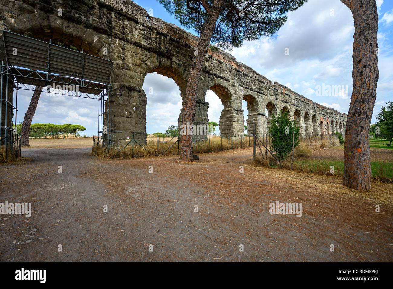 Klassisches Aquädukt aus Stein, das rhythmische Bögen im grünen Park des Parco degli Acquedotti in Rom bildet. Stockfoto
