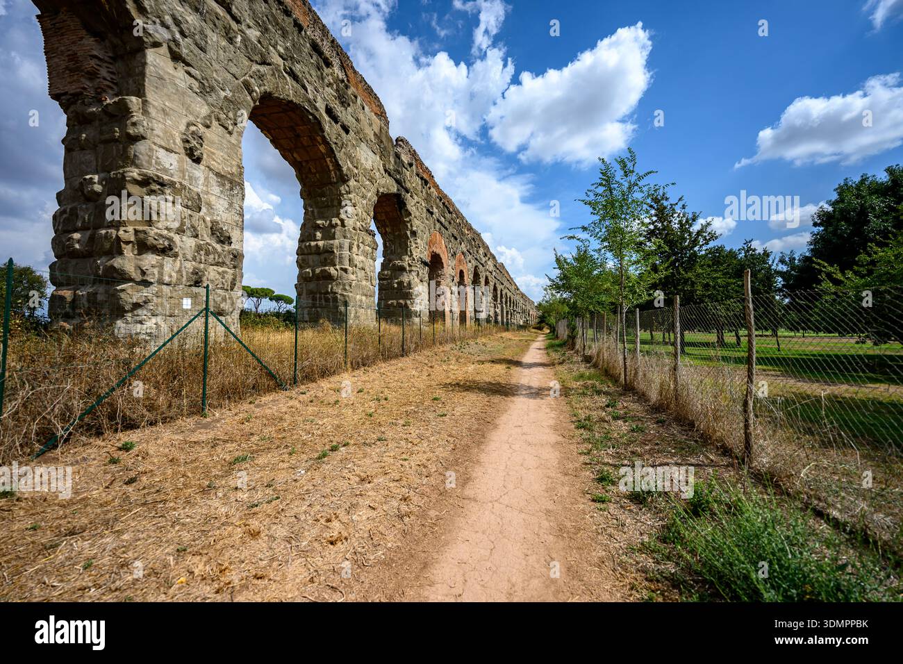 Im Parco degli Acquedotti, einem historischen Landschaftsgebiet in Rom, Italien, erheben sich antike Aquäduktbögen über offenes Parkgelände. Stockfoto