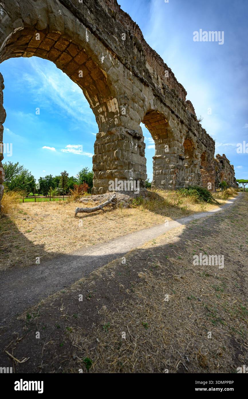 Klassisches Aquädukt aus Stein, das rhythmische Bögen im grünen Park des Parco degli Acquedotti in Rom bildet. Stockfoto