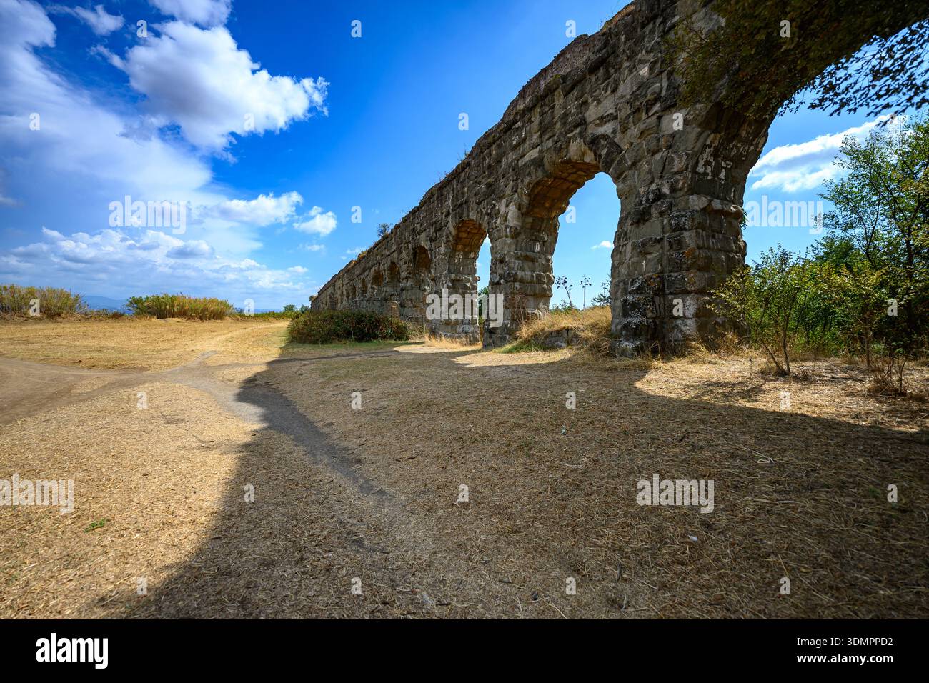 Großer Außenblick auf die römische Aquäduktarchitektur, integriert in die Landschaft des Parco degli Acquedotti, Rom. Stockfoto