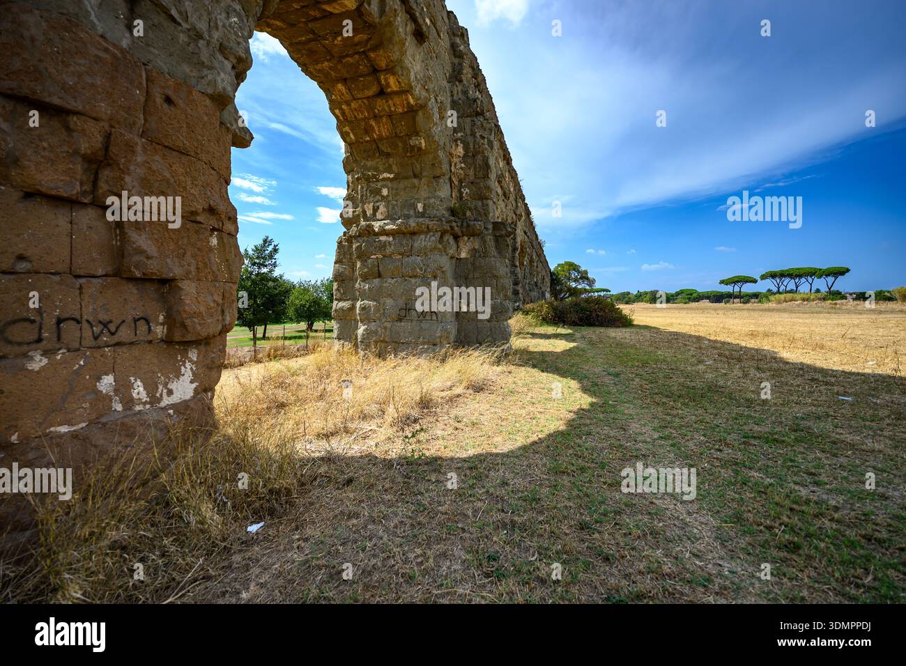 Im Parco degli Acquedotti, Rom, erstrecken sich erhaltene römische Aquäduktbögen über das Gelände mit Kiefern. Stockfoto