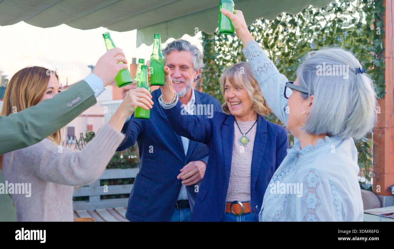 Freunde, die mit Flaschen tosten, genießen eine Dachparty Stockfoto