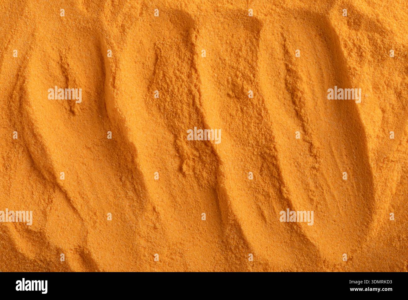 Kurkumapulver erscheint als warmes, fein strukturiertes goldenes Material, das natürlichen Ursprung, Authentizität und eine klare, ausgewogene Optik vermittelt. Stockfoto