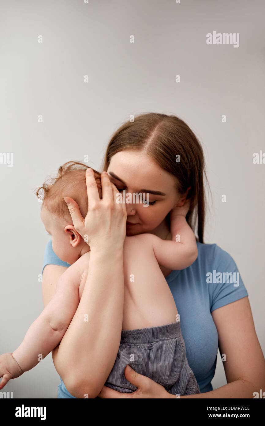 Liebevolle Umarmung zwischen Mutter und Kind unterstreicht Zärtlichkeit und Verbundenheit in einer gemütlichen Innenumgebung und zeigt die pflegende Bindung zwischen Mutter und Kind Stockfoto
