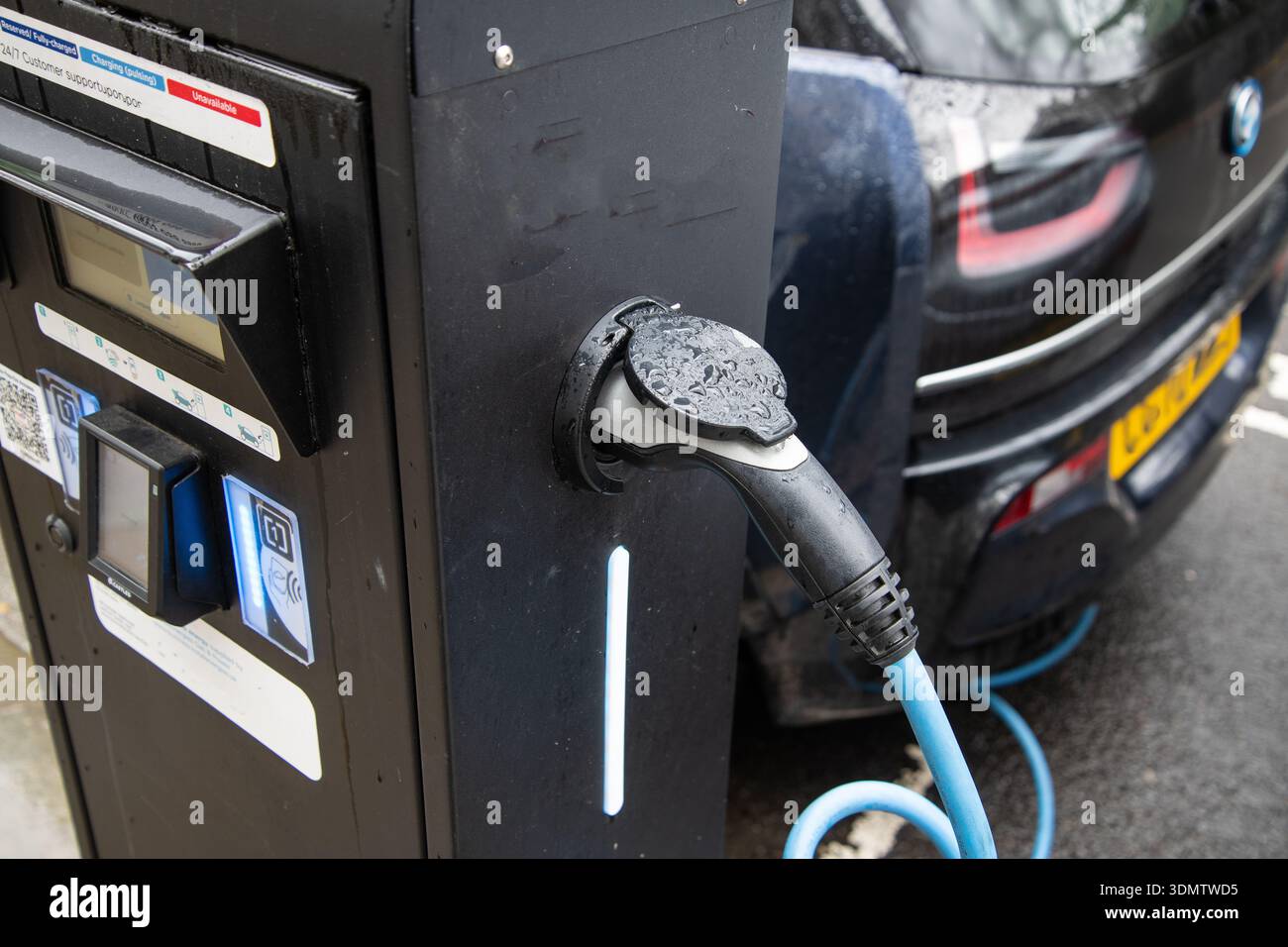 Nahaufnahme eines Ladeanschlusses für Elektrofahrzeuge, der an ein modernes Auto angeschlossen ist und nachhaltige Energie und EV-Technologie hervorhebt. Stockfoto