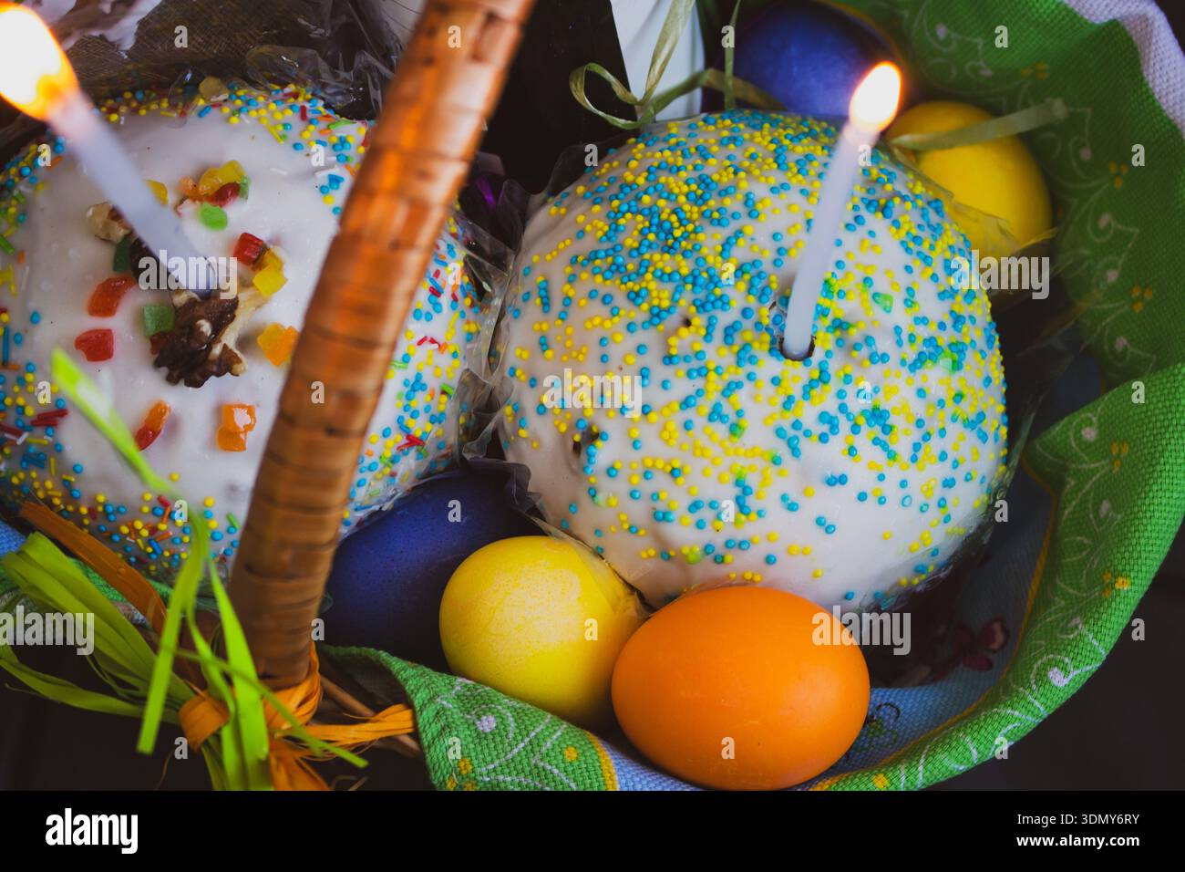 Osterkuchen mit bemalten Eiern und Kerzen in einem Korb. Osterstillleben. Orthodoxe Eater-Feier. Bunte Ostereier mit süßem Kuchen im Korb Stockfoto