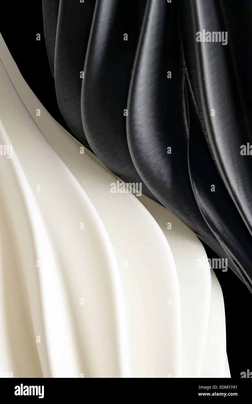 Abstrakte Nahaufnahme von schwarz-weißen Kunststoffwellen, die ein strukturiertes Muster erzeugen. Die glatten Materialien bilden gewellte Kurven und sorgen für ein elegantes und Stockfoto