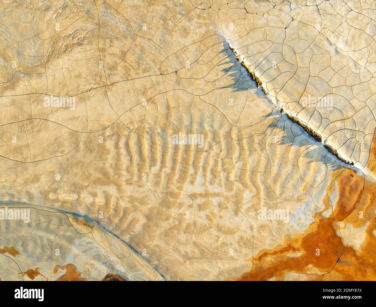 Aus der Vogelperspektive zeigt eine beeindruckende Landschaft aus rissigem, kontaminiertem Boden mit reichhaltigen Texturen und Erdtönen. Die Oberfläche zeigt komplexe Muster und Stockfoto
