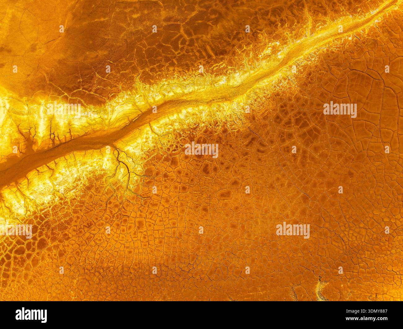 Eine Luftaufnahme von kontaminiertem Boden zeigt eine auffällige goldene Textur. Die komplizierten Muster und Risse verdeutlichen die Auswirkungen von Umweltveränderungen Stockfoto