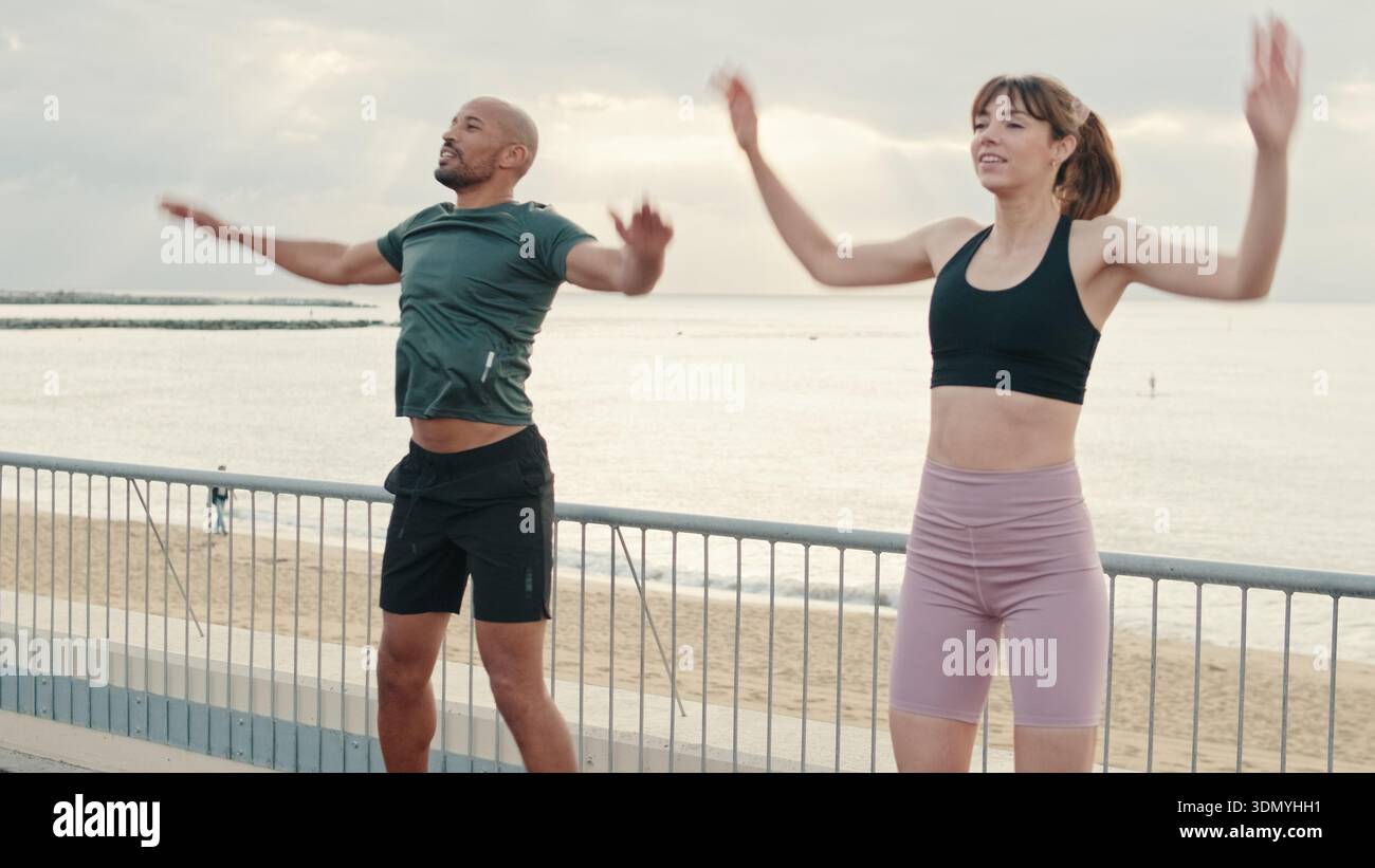 Multi-ethnische Männer und Frauen, die gemeinsam ein dynamisches Kardio-Workout machen, sich auf körperliche Aktivität vorbereiten und als Team trainieren. Paar Tore und Sportmot Stockfoto
