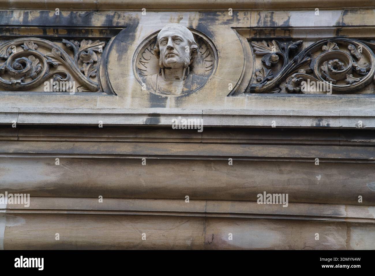 Kunstvoll geschnitzte Porträtbüste mit Scrollarbeiten an einer historischen Fassade des Gebäudes von Cambridge. Cambridge, England Stockfoto