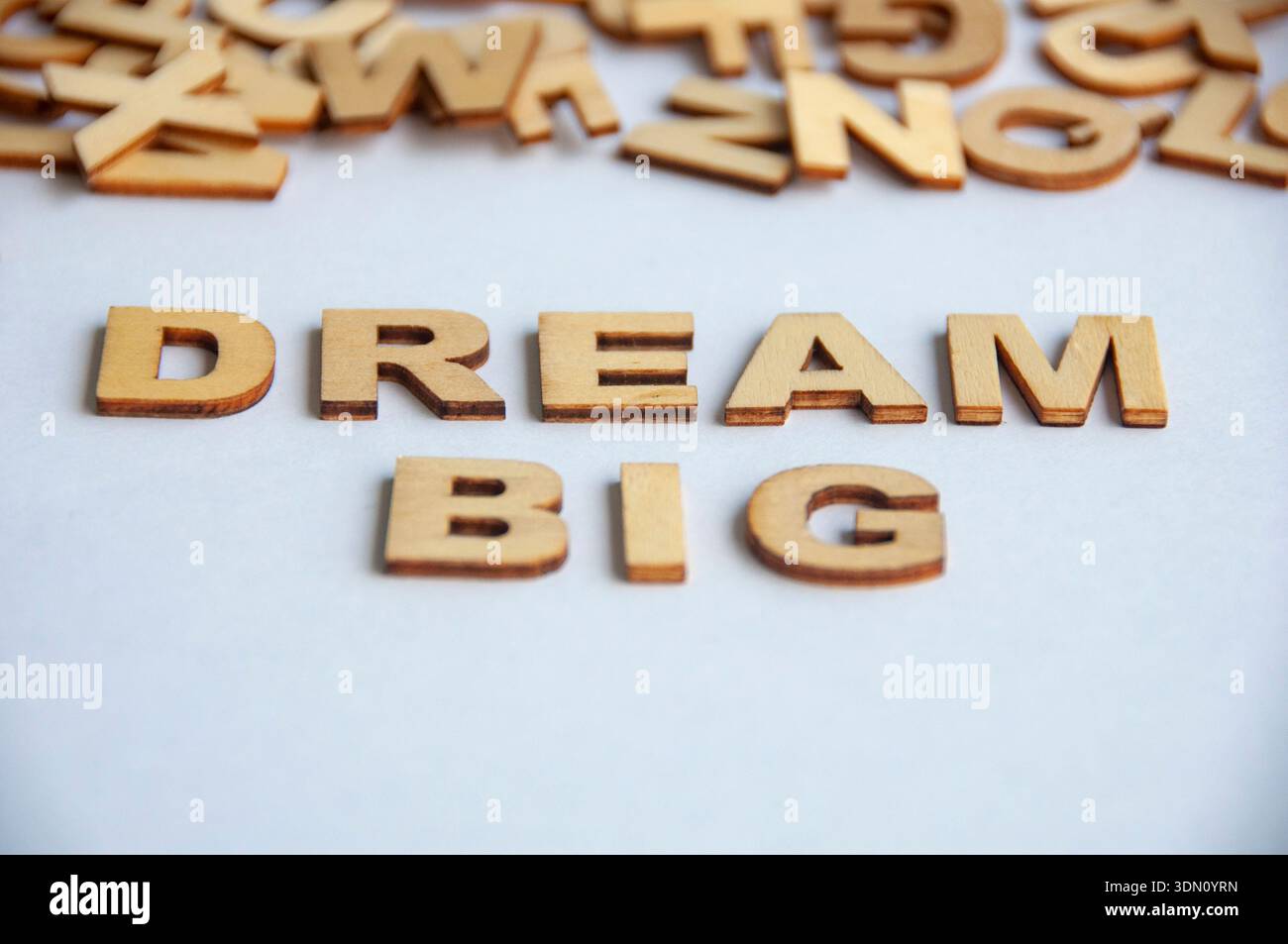 Großer Text aus Holzbuchstaben auf weißem Hintergrund, der Ehrgeiz, Motivation und persönliches Wachstumskonzept symbolisiert. Stockfoto