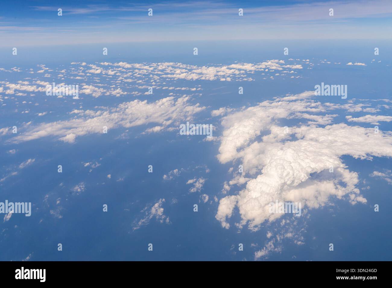 Tagsüber sind Wolken über dem Ozean verstreut. Der blaue Himmel erstreckt sich darüber, und die Szene zeigt verschiedene Formen und Größen von Wolken gegen die Stockfoto
