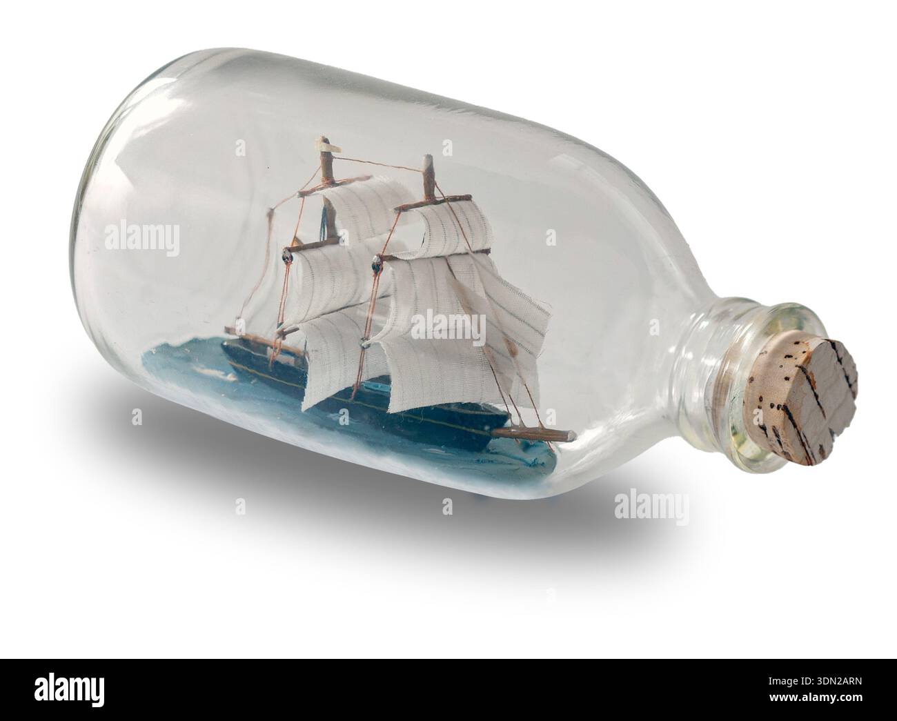 In einer Flasche versenden. Kleines Schiffsmodell in einer Flasche mit Korkstopfen auf weißem Hintergrund. Stockfoto