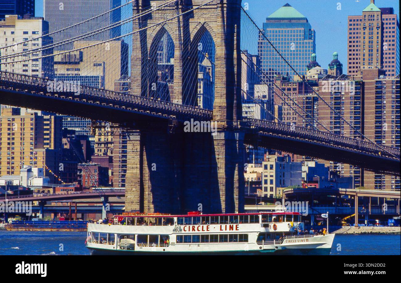 USA, New York City, Brooklyn Bridge mit einem Circle Line Sightseeing Cruises Boot auf dem East River im Vordergrund. Stockfoto