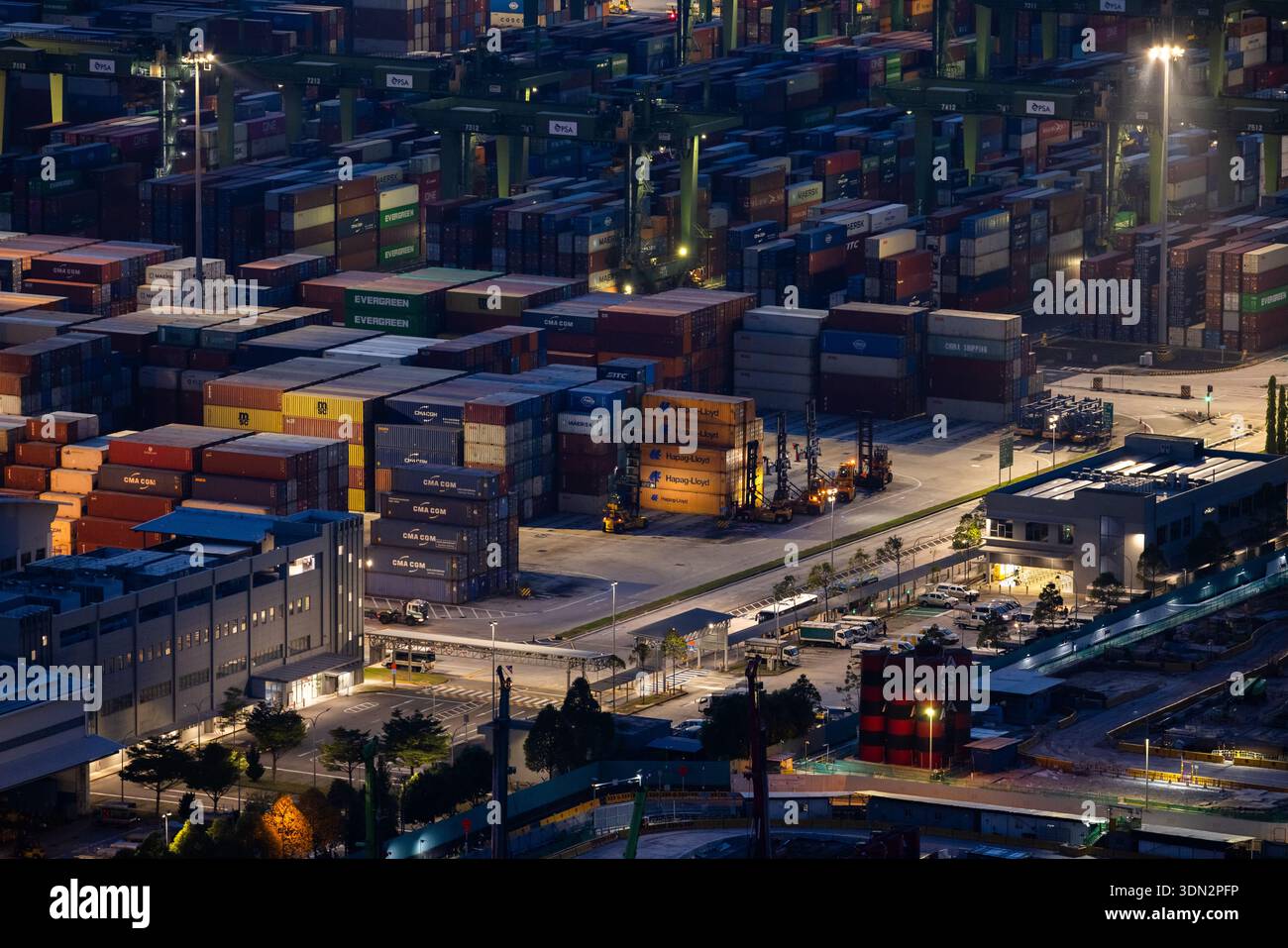 Blick auf den Hafen von Singapur in der Abenddämmerung mit Frachtschiffen, Containern und Kränen am Pasir Panjang Terminal Stockfoto