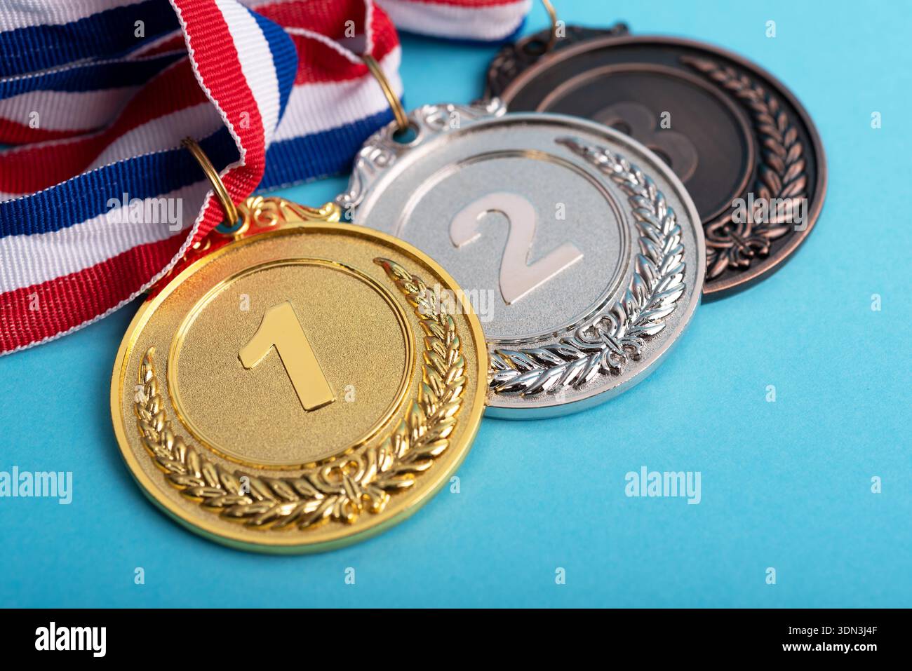 Hochwinkelansicht von Gold-, Silber- und Bronzemedaillen auf blauem Hintergrund Stockfoto