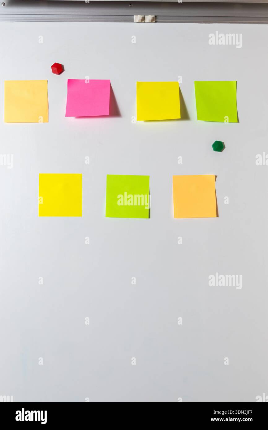 Sieben bunte, leere Haftnotizen auf einer weißen Whiteboard-Oberfläche. Für Brainstorming, Teamplanung, Erinnerungen, Konzepte und Kommunikation Stockfoto