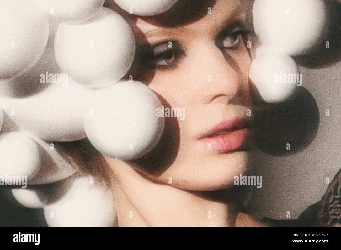 Junge Frau posiert mit einem künstlerischen und konzeptionellen Styling mit weißen Bällen Stockfoto