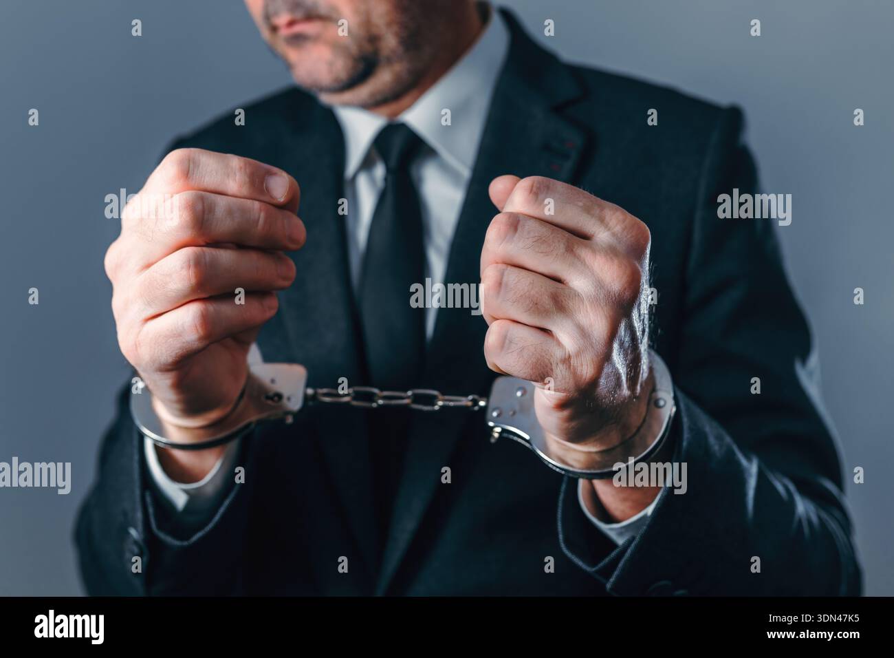 Nahaufnahme eines verhafteten Geschäftsmannes in Anzug, der Handschellen trägt und Verbrechen, Korruption, Betrug und rechtliche Konsequenzen in Unternehmen und Finanzen symbolisiert Stockfoto