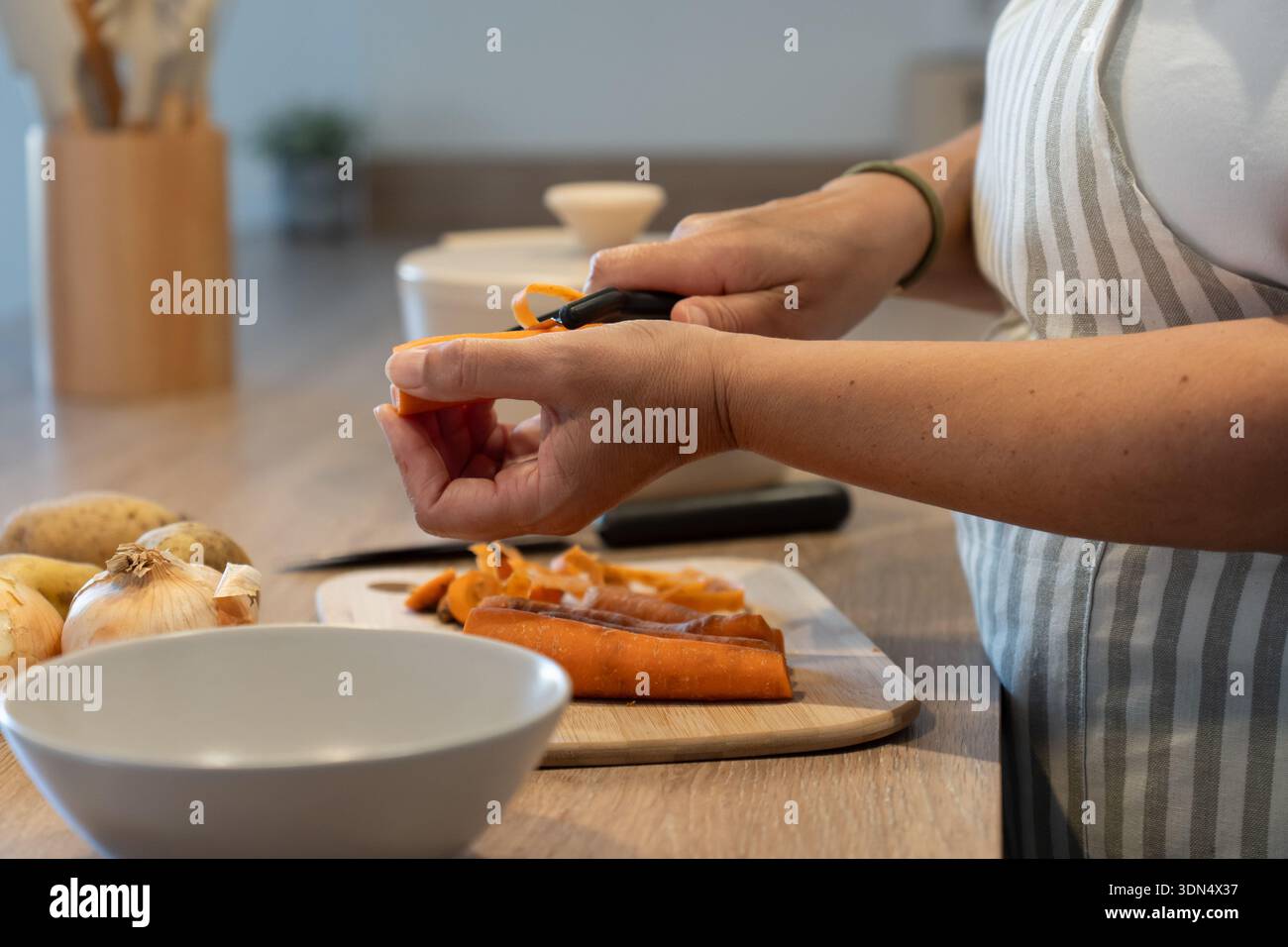 Hände schälen Karotten für hausgemachte Mahlzeiten. Sauberes Essen, einfache Zutaten und gesundes Lebensstil Konzept. Stockfoto