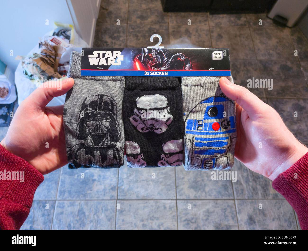 Ein Mann mit Star Wars-Socken als Weihnachtsgeschenk in England, Großbritannien. Socken mit neuem Thema decken eine Vielzahl von Themen und Interessen ab Stockfoto