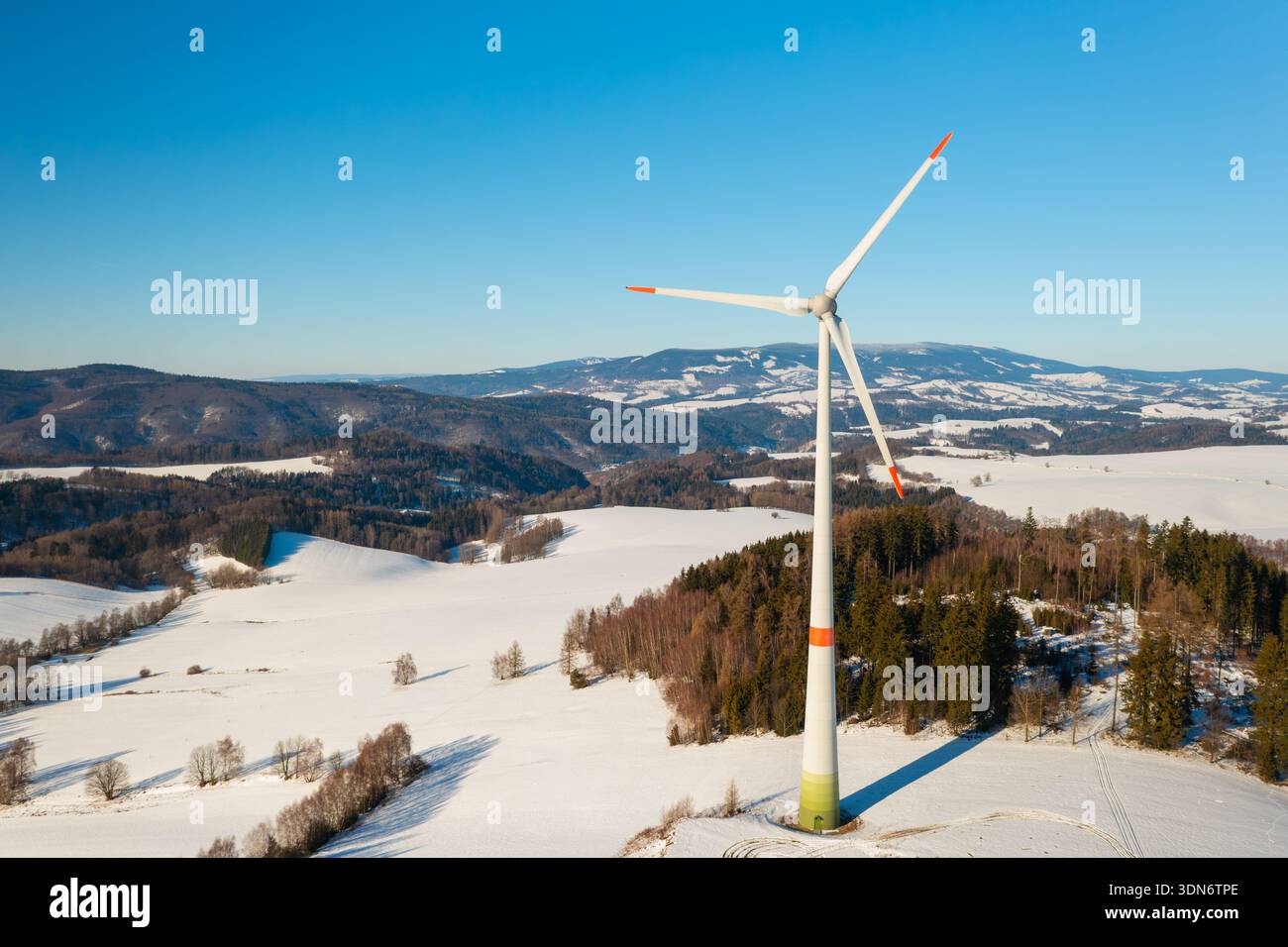 Windenergieanlage, die auf einem verschneiten Winterfeld betrieben wird. Konzept der Energieunabhängigkeit und der nachhaltigen Elektrizität. Stockfoto
