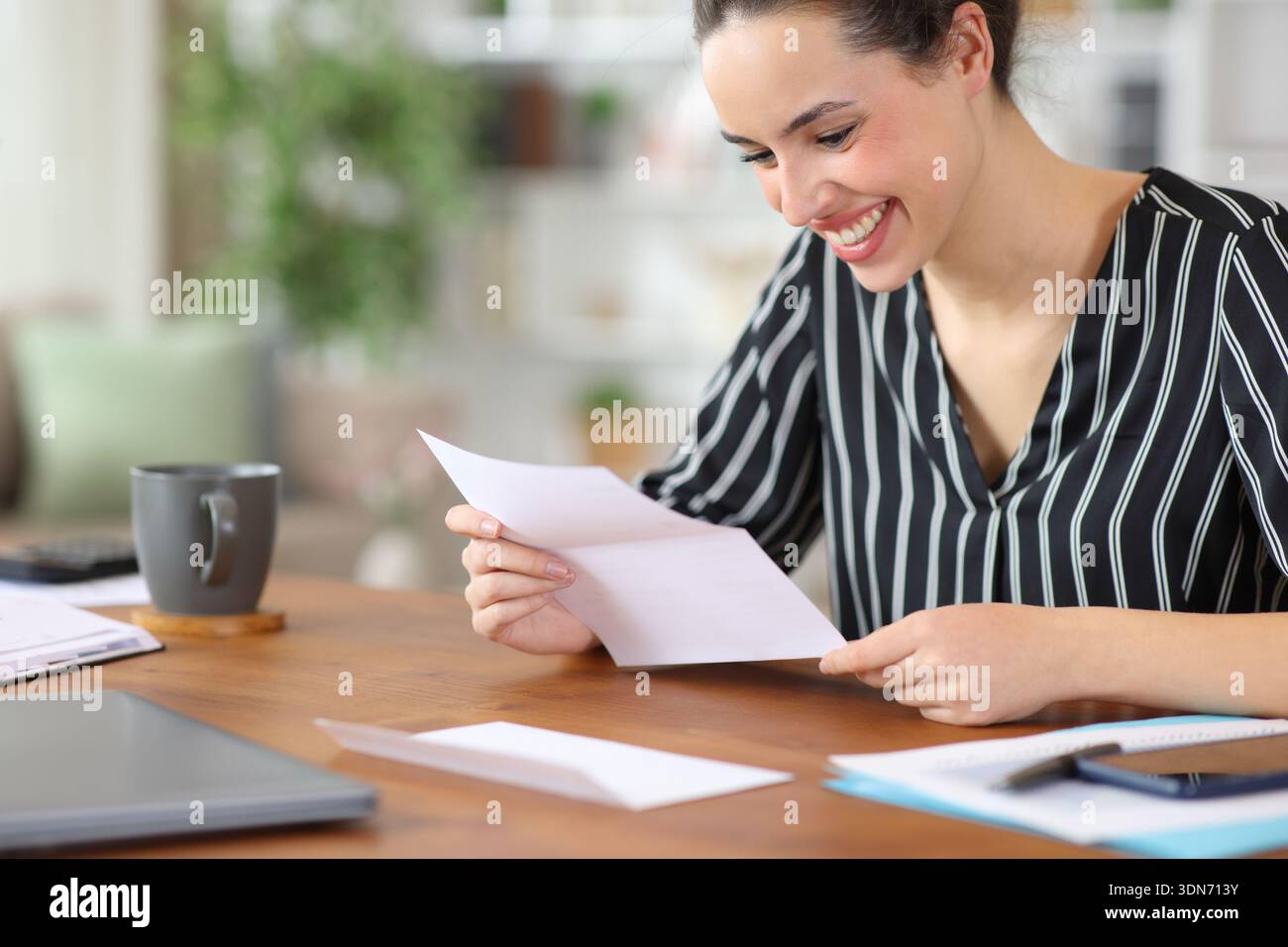 Glücklicher Telearbeiter, der Briefe liest und zu Hause arbeitet Stockfoto