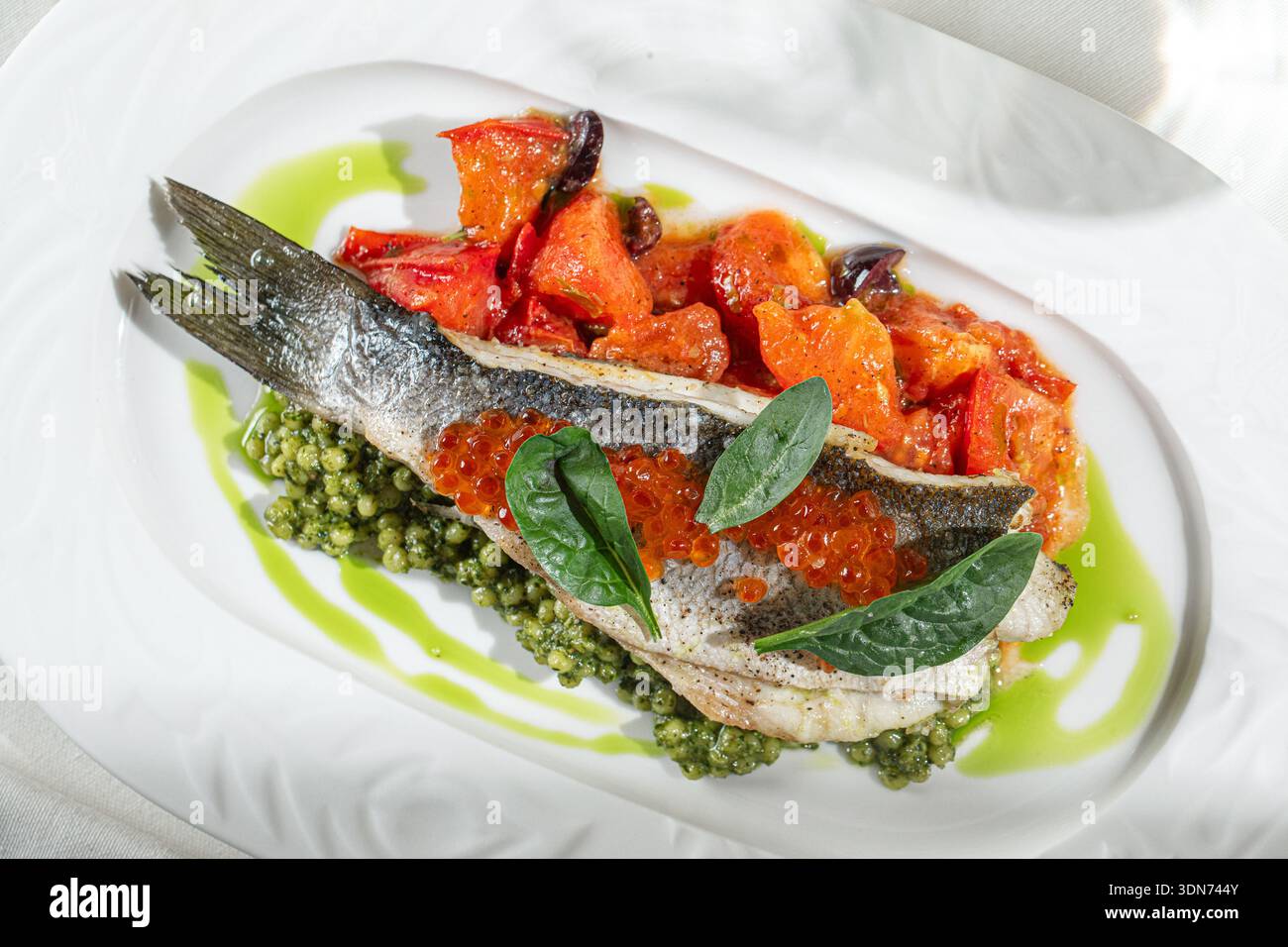 Gebratenes Fischfilet mit Gemüse und grüner Sauce Stockfoto