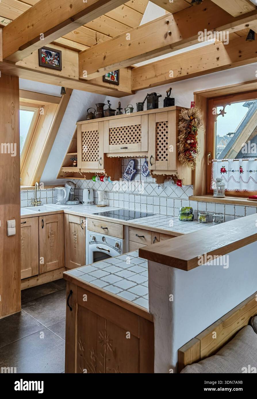 Gemütliche rustikale Küche mit Holzbalken und gefliesten Theken - Smartphone-aufgenommenes Stockfoto