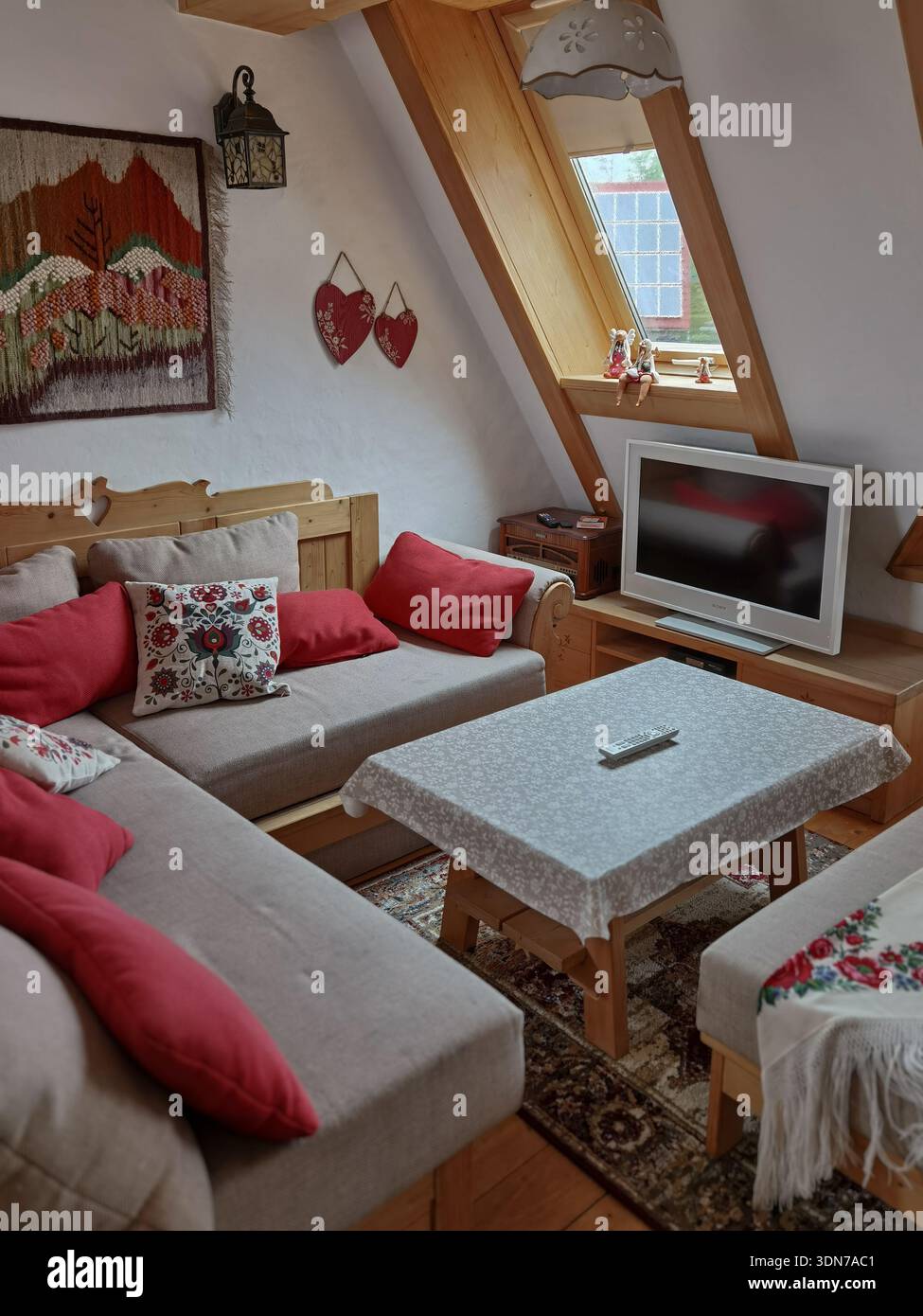 Gemütliches Wohnzimmer im Dachgeschoss mit rustikalen Holzmöbeln und traditioneller Einrichtung - Smartphone-aufgenommenes Stockfoto