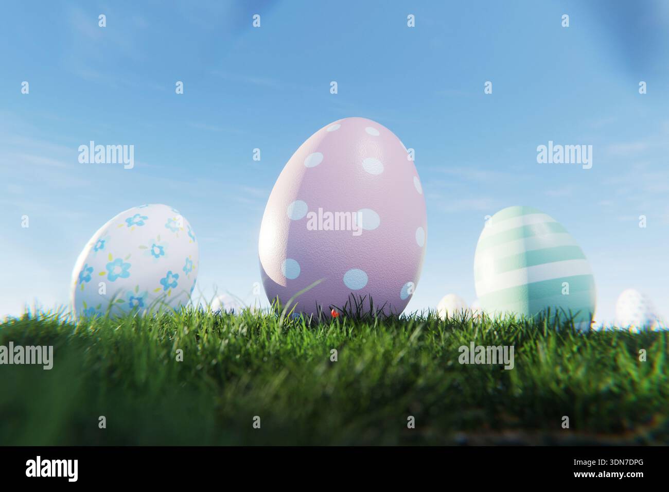 Nahaufnahme dekorativer Ostereier mit pastellfarbenen Polka Dots und Blumenmustern in grünem Gras. Ei mit klarem blauem Himmel Hintergrund, perfekt für den Frühling Stockfoto