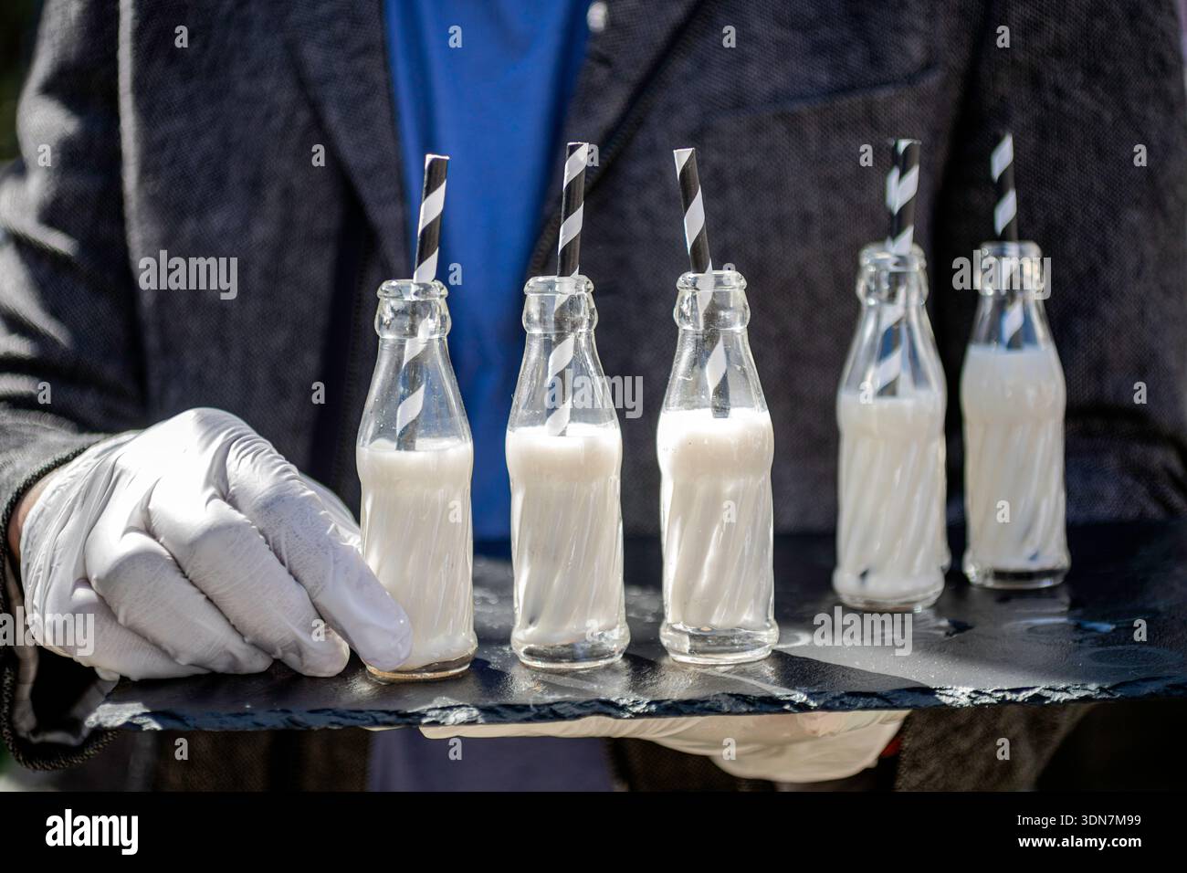 Miniaturglasflaschen mit Milch und Strohhalm bei der Veranstaltung Stockfoto