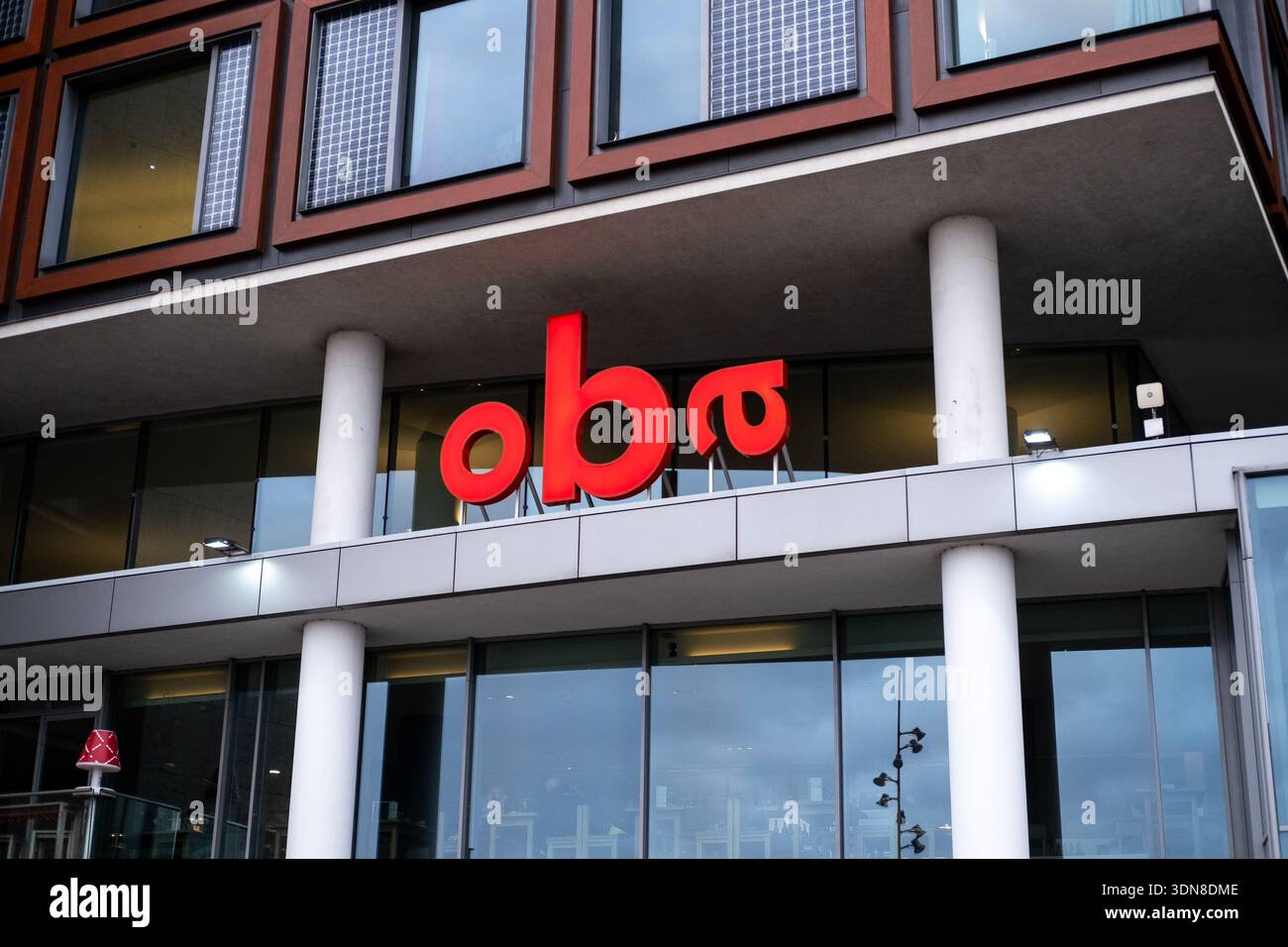 Außenansicht der Fassade der öffentlichen Bibliothek OBA Centrale mit dem roten oba-Schild und den Solarpaneelen für Fenster, Amsterdam, Noord-Holland, Niederlande, Stockfoto