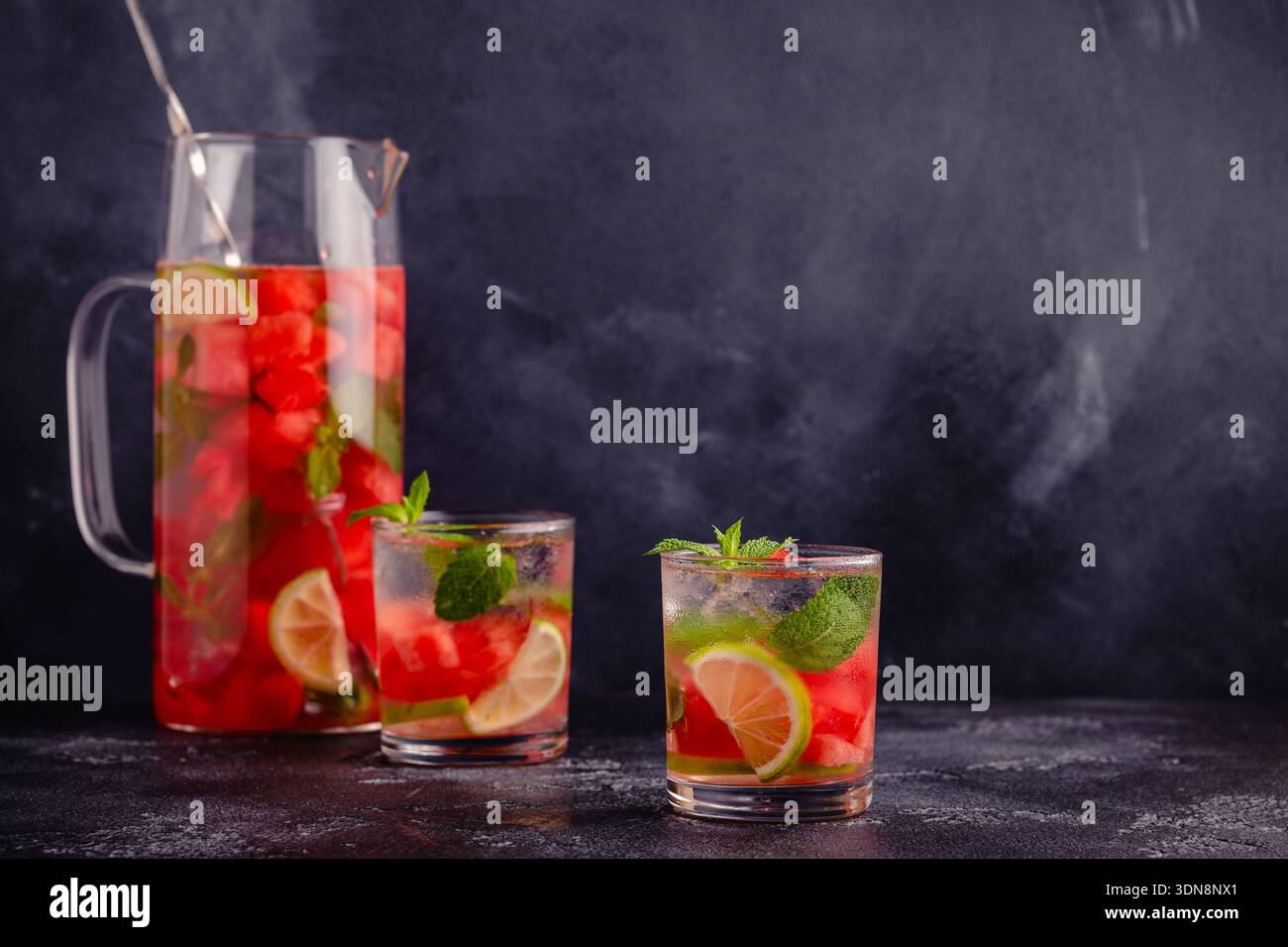 Wassermelonen-Infusionswasser mit Limette und Minze in einer Kanne und Gläsern. Stockfoto