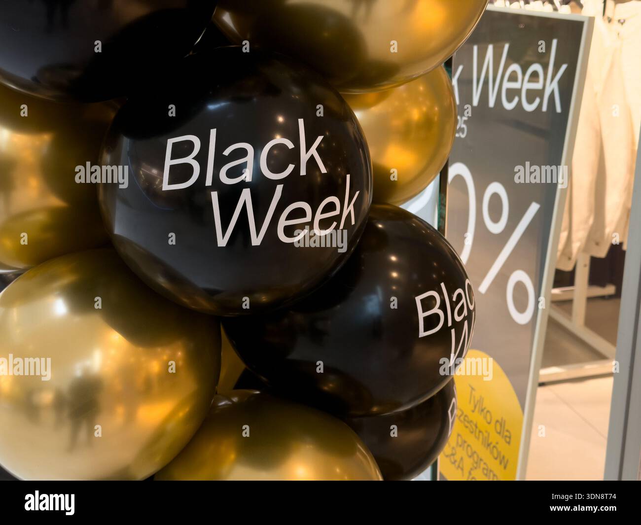 Aus nächster Nähe sehen Sie leuchtende schwarze und goldene Ballons mit dem „Black Week“-Schriftzug, die saisonale Sonderangebote und große Rabatte in einem Einzelhandelsgeschäft hervorheben Stockfoto