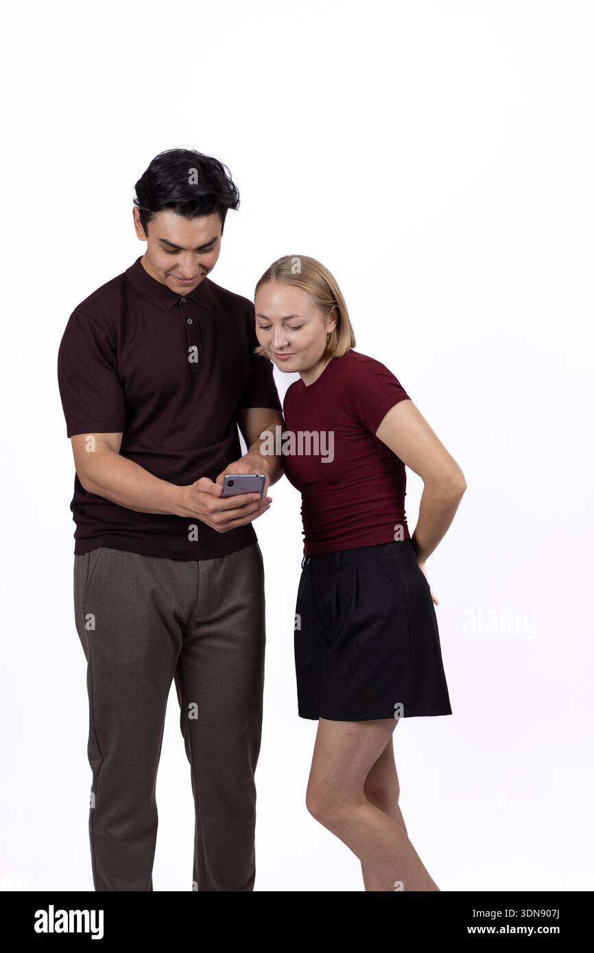 Junger Mann und Frau, die zusammen im Studio auf das Smartphone schauen Stockfoto