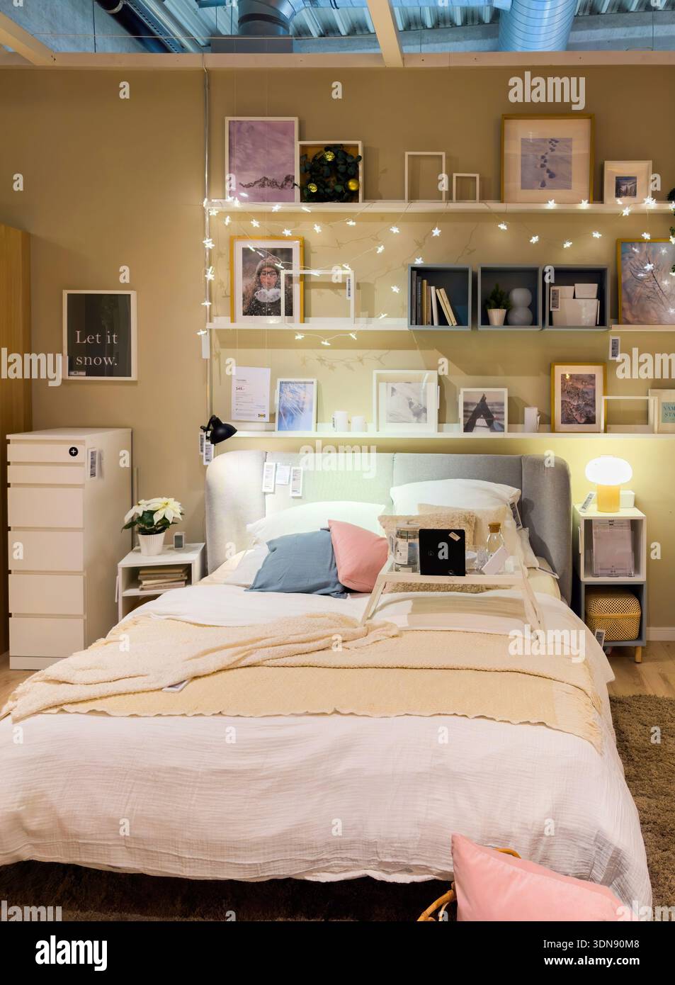 Freiburg, Deutschland - 29. Dez. 2025: Gemütliches Schlafzimmer-Showroom-Setup im IKEA Store mit gemütlichem Bett mit beigefarbener Bettwäsche, pastellfarbenen Kissen, Wandregalen mit Rahmen, Feenlichtern und modernen Möbeln Stockfoto