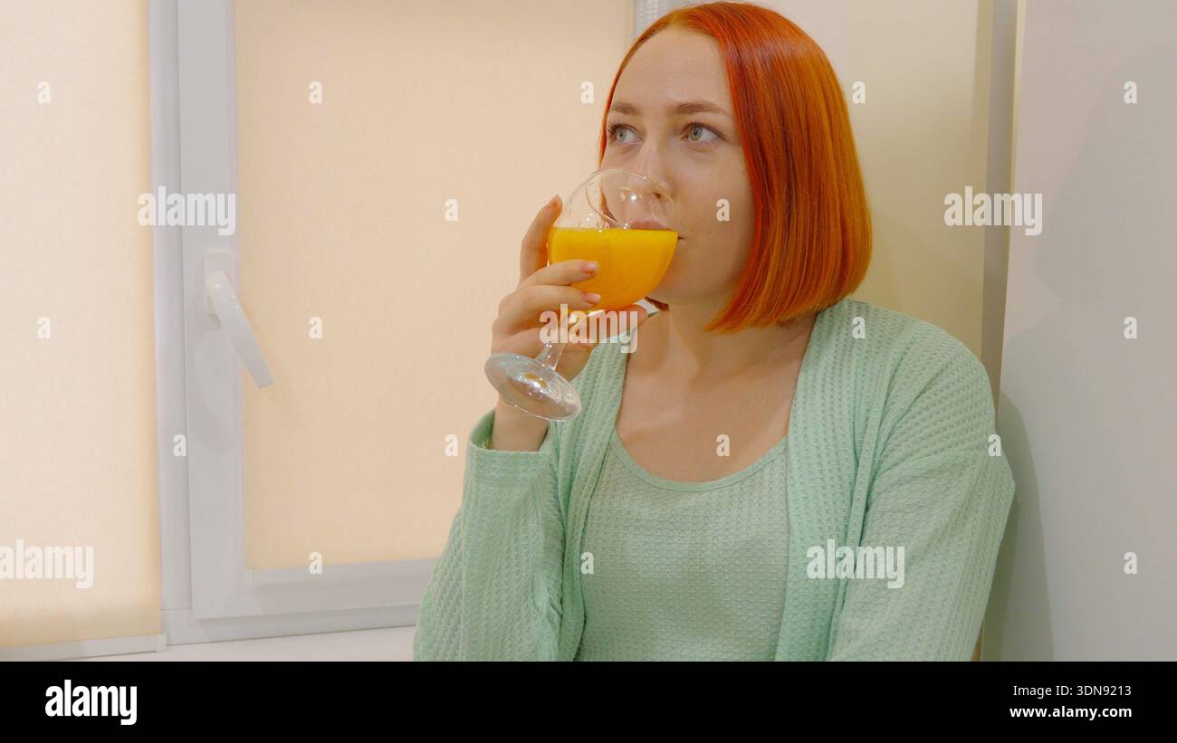 Frau trinkt frischen Orangensaft in der Küche Stockfoto