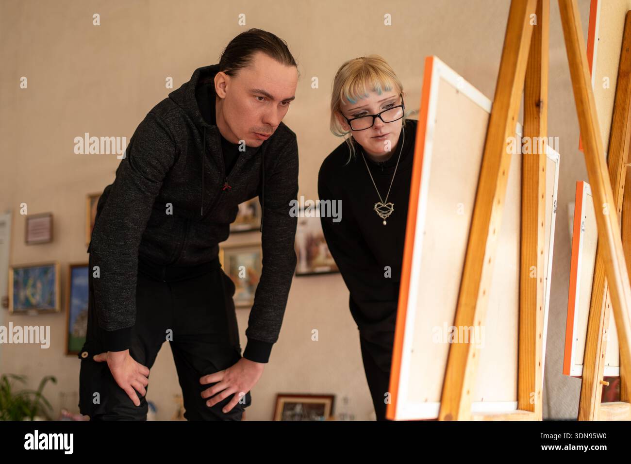 Ein Mann und eine Frau stehen zusammen und betrachten ein Gemälde in einer Kunstgalerie oder einem Museum, um ein Datum oder ein gemeinsames kulturelles Erlebnis vorzuschlagen. Stockfoto