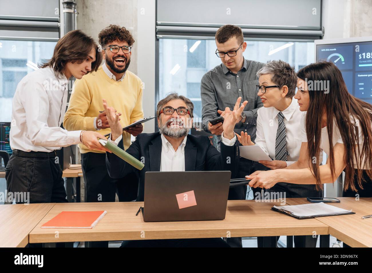Ein vielseitiges Team von Geschäftsleuten arbeitet aktiv in einem modernen Büroumfeld zusammen, umgeben von Technologie und Diagrammen, um die Energie hervorzuheben Stockfoto