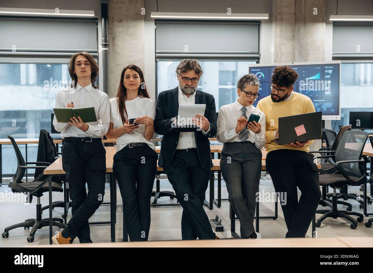 Vielfältige Gruppe von Geschäftsleuten in einer modernen Büroumgebung, die mit digitalen Geräten zusammenarbeiten, Teamarbeit und Innovation demonstrieren Stockfoto