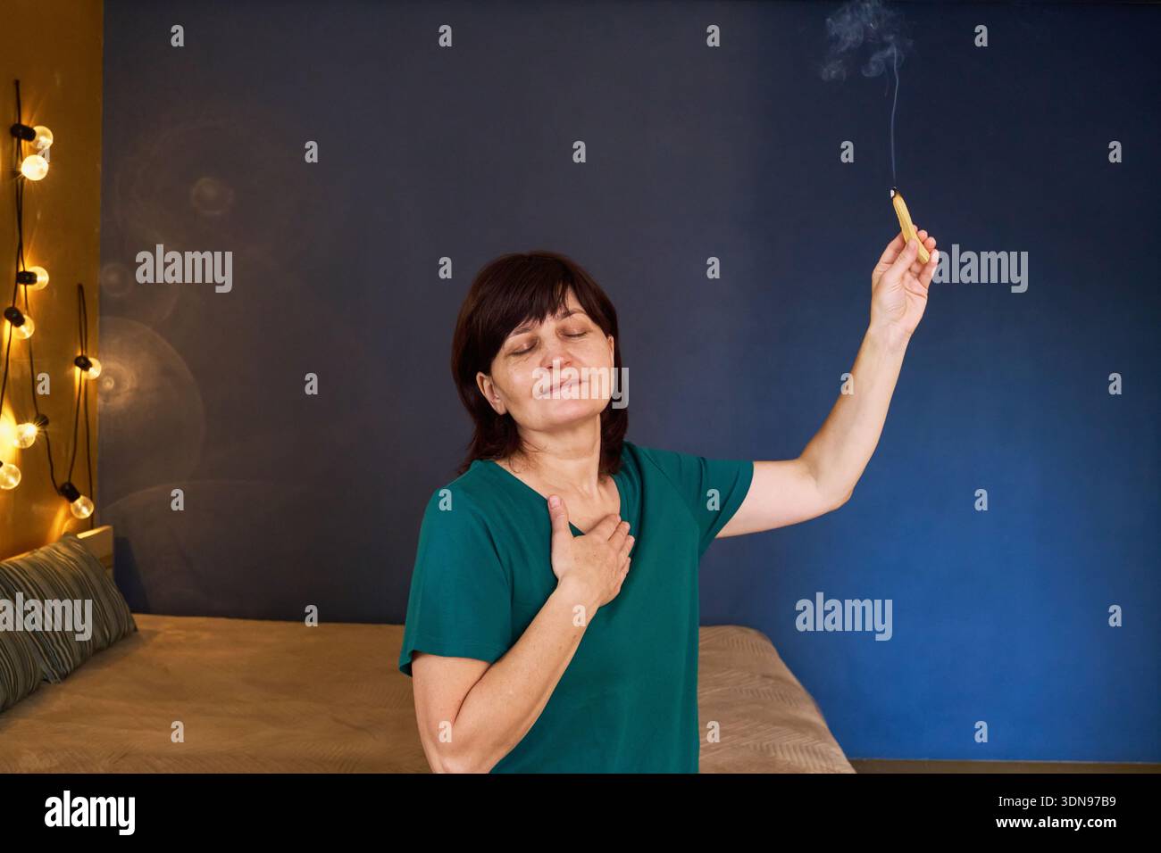 Frau, die Reinigungsritual mit brennendem palo santo Holz und geschlossenen Augen durchführt Stockfoto