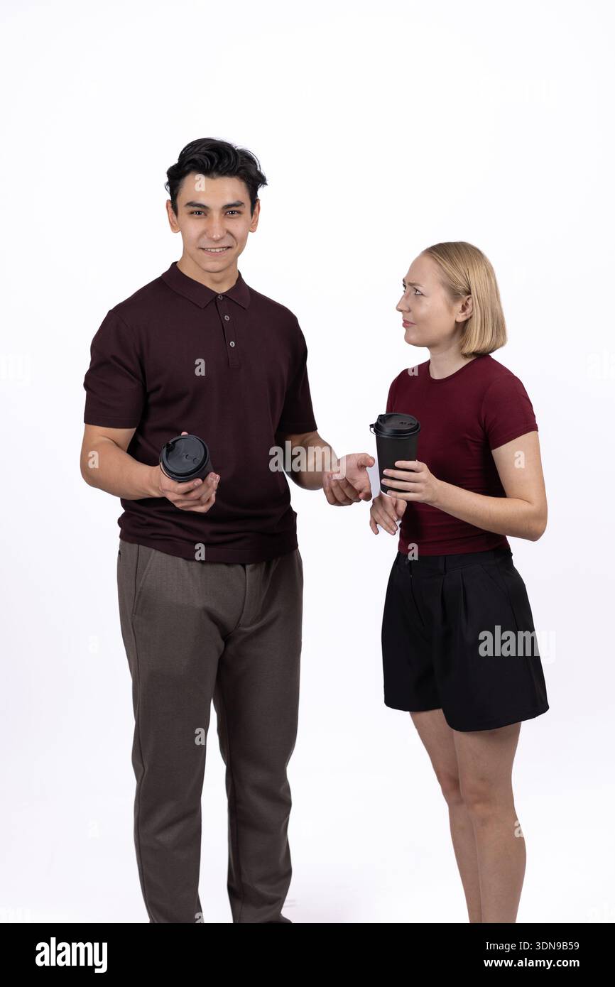 Mann und Frau halten Tassen und reden im Studio Stockfoto