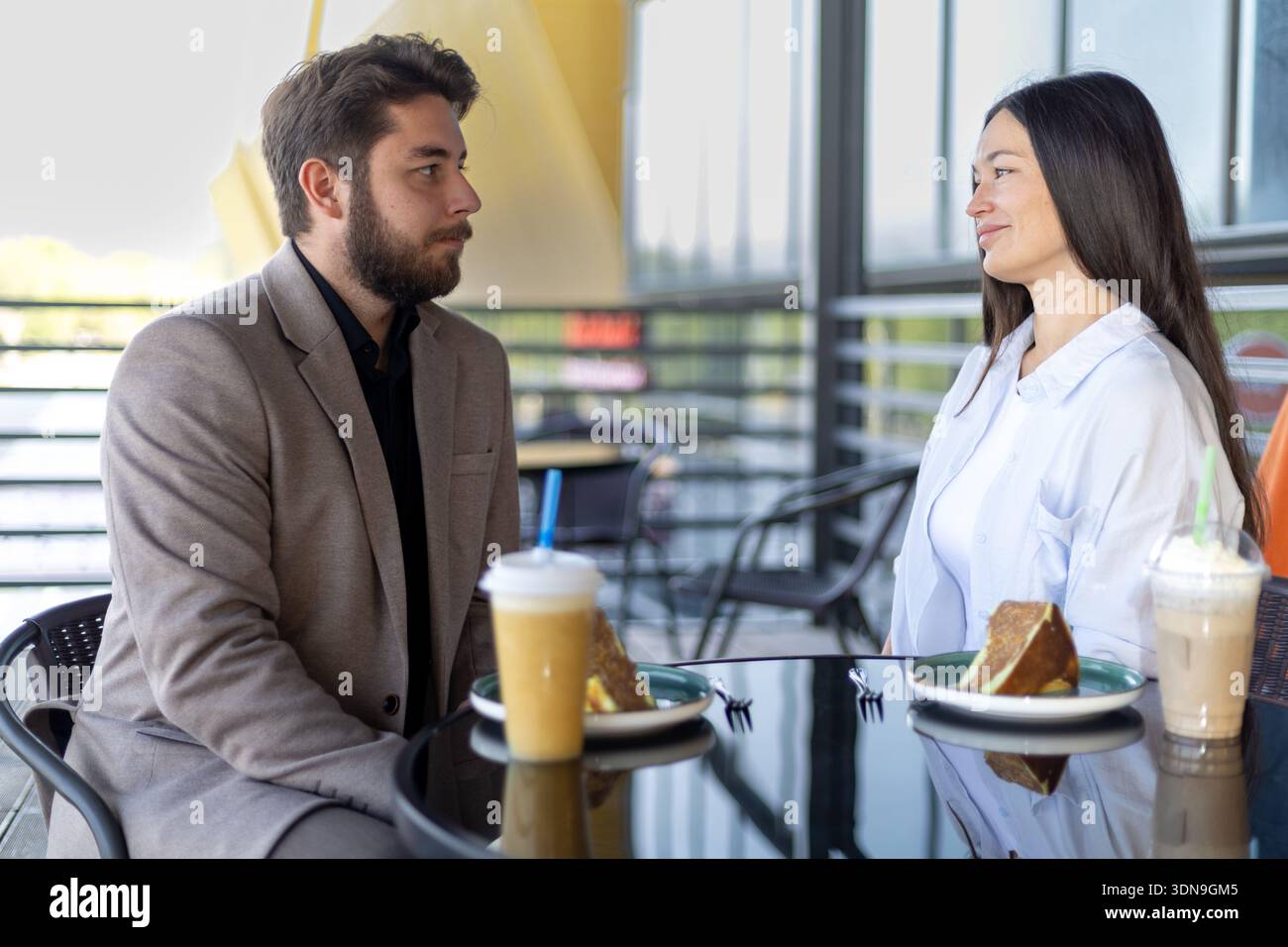Mann und Frau unterhalten sich im Straßencafé Stockfoto