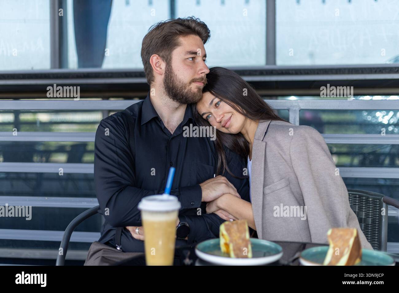 Pärchen sitzen am Café-Tisch und unterhalten sich miteinander Stockfoto