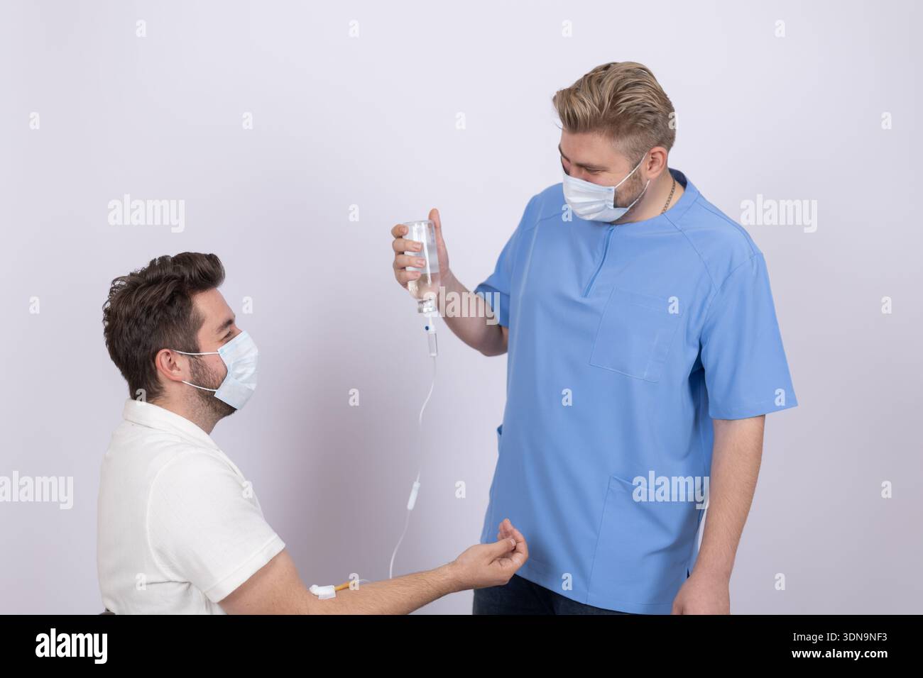 Mann, der mit einem anderen Mann in blauer medizinischer Uniform spricht Stockfoto